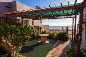 a pergola with a picnic table in a garden at Baja Beach House Pools, Beaches & Ocean View in San Antonio del Mar