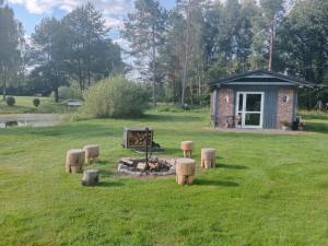 a cabin in a field with a fire in the grass at Domek Leśny Zakątek z klimatyzacją in Bartel Wielki