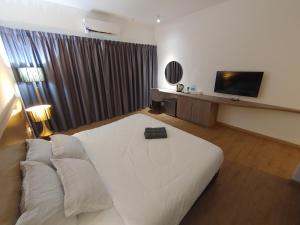 a hotel room with a white bed and a television at Sofea Roomstay Hotel in Kota Bharu