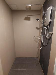 a bathroom with a shower with a mirror and a tile floor at Sofea Roomstay Hotel in Kota Bharu