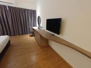 a room with a desk with a television on a wall at Sofea Roomstay Hotel in Kota Bharu