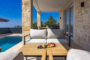 a patio with a couch and a table next to a pool at Villa Bella Vista with Pool and Seaview in Labinci +23 photos