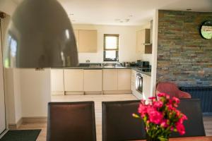 a kitchen with white cabinets and a table with pink flowers at Oak Lodge in Knighton