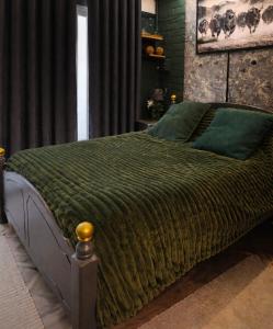 a bedroom with a bed with a green comforter at Arena Apartment Meadowhall in Brightside