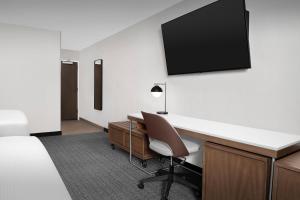 a hotel room with a desk and a tv on the wall at Courtyard by Marriott Portland Tigard in Tigard