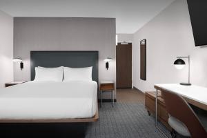 a bedroom with a large white bed and a desk at Courtyard by Marriott Portland Tigard in Tigard