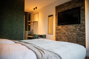 a hotel room with a bed and a flat screen tv at Hotel Biedeboom in 's-Heer-Hendrikskinderen