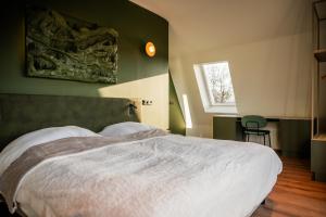 a bedroom with a white bed with a green wall at Hotel Biedeboom in 's-Heer-Hendrikskinderen +24 photos