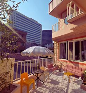 a balcony with a table and chairs and an umbrella at SoSi Stay in Seoul