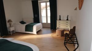 a bedroom with two beds and a dresser and a window at Entre pierre & vigne in Arrentières