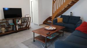 a living room with a blue couch and a tv at Entre pierre & vigne in Arrentières
