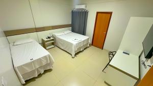 ein Krankenzimmer mit zwei Betten und einem Spiegel in der Unterkunft Hotel Ideal 5 in Araguaína + 17 Fotos