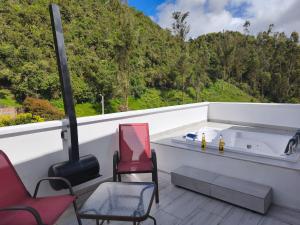 a balcony with chairs and a bath tub with a view at Mirador samsara Jacuzzi al aire libre 60 m2 in La Calera