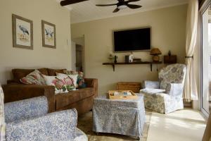 a living room with a couch and a chair and a tv at Featherwood Cottage in Malgas
