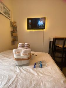 a bed with towels and cups and a tv on the wall at Casa Ona in Manila +3 photos