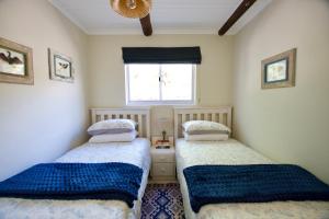 two beds in a small room with a window at Featherwood Cottage in Malgas