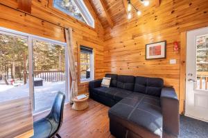 a living room with a black leather couch in a cabin at Le Sherwood #4 Shannon in Valcartier Station +23 photos