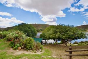 a view of a river with trees and a fence at Featherwood Cottage in Malgas