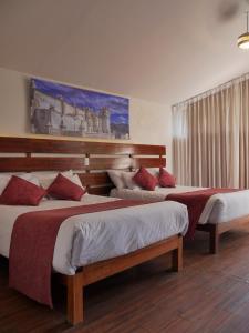 a bedroom with two beds and a painting on the wall at Casona Urinsaya Qolca in Chivay