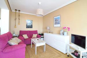 ein Wohnzimmer mit einem rosa Sofa und einem Fernseher in der Unterkunft Comillas playa in Comillas