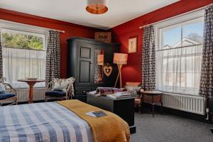 a bedroom with a bed and red walls and windows at One Drake Road Hotel in Tavistock