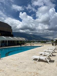 a row of lounge chairs next to a swimming pool at Hotel CCT Caracas in Caracas