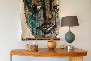 a table with a lamp and a painting on the wall at Villa Joséphine in Grand-Bourg