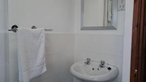 a white bathroom with a sink and a mirror at C35 Le Grace, Riviere Towans in Hayle