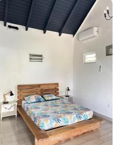a bedroom with a wooden bed and white walls at Blue dream Bungalow in Le Gosier