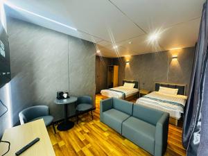 a room with two beds and a couch and a table at Mandala Hotel Erdenet in Erdenet