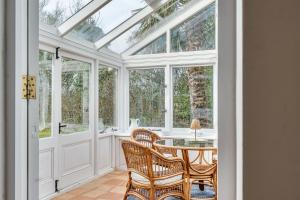 a conservatory with a table and chairs and windows at Amys Cottage in Sherborne