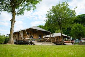 a large building with a tree in the grass at Glamping Costa Dorada in Vilanova i la Geltrú