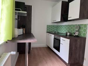 a small kitchen with white cabinets and green tiles at Ferienwohnung 1A in Fockendorf