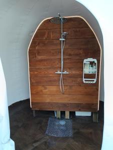 a shower in a room with a wooden wall at Les Bulles du Coq de Champagne in Dormans