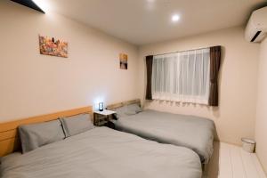 two beds in a small room with a window at ララリカ in Kami-furano