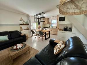a living room with a black leather couch and a kitchen at "ZeeLandZon" Holiday home by the lake with Jacuzzi and Sauna in Herkingen