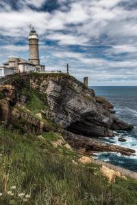a lighthouse sitting on top of a cliff next to the ocean at Villa Mayki in Cacicedo