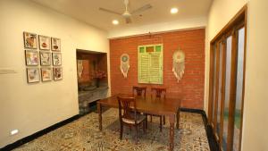 a dining room with a table and chairs and a brick wall at VILLA De OMR, Private Pool Villa at Old Mahabalipuram Road, Chennai in Kelambākkam