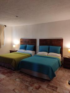 a bedroom with two beds with blue and green sheets at Departamento Deli in Cancún