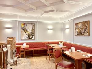 a restaurant with tables and chairs and paintings on the walls at Hotel Kriemhild am Hirschgarten in Munich