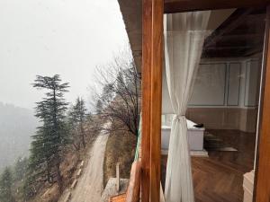 a room with a window with a view of a dirt road at The Swayambhu Hamta in Manāli