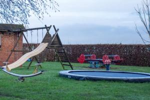 a playground with two swings and a slide at De Horizon in de Westhoek in Poperinge