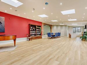 a large room with a red wall and a table and chairs at 1 Bed in Lutterworth oc-93761 in Boughton