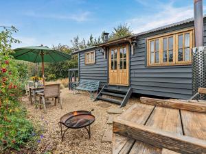 a house with a grill and a table and an umbrella at 1 Bed in Lutterworth oc-93760 in Boughton
