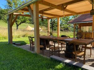 a wooden table and chairs under a pavilion at Camping équipé : Vallon de Laborie in Astaillac