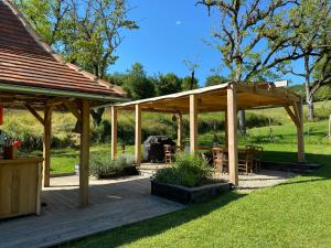 a wooden pavilion with tables and chairs in a yard at Camping équipé : Vallon de Laborie in Astaillac +6 photos