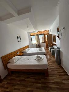 a room with two beds and a desk at Beleris Rooms in Himare