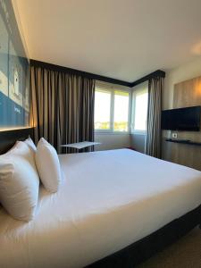 a hotel room with a large bed with white pillows at ibis Styles Flers in Flers