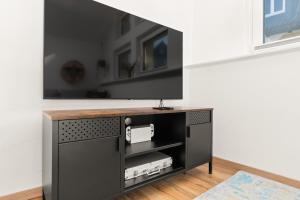 a black entertainment center with a flat screen tv on a wall at KOLIBRI - Design Maisonette - Nintendo Switch, Streaming, Bikestore, E-Wallbox in Marburg an der Lahn