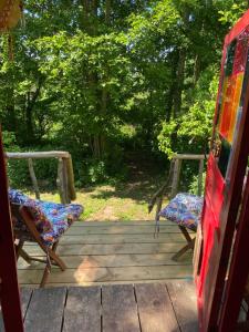 two chairs sitting on a wooden porch with trees at The Shangri La Sunset Yurt in Tenbury +13 photos